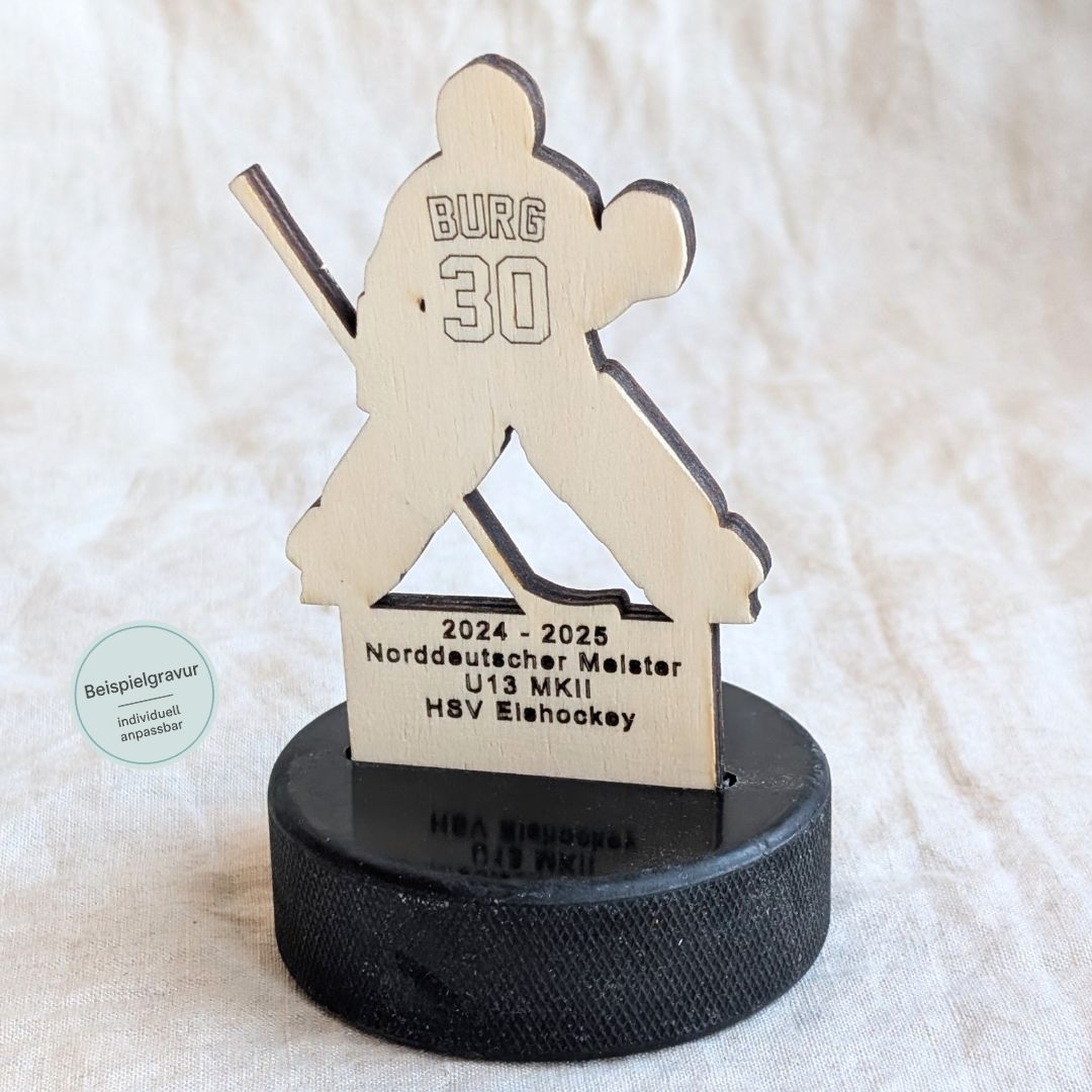 Detailaufnahme eines personalisierten Goalie-Pokals aus Holz auf Eishockey-Puck