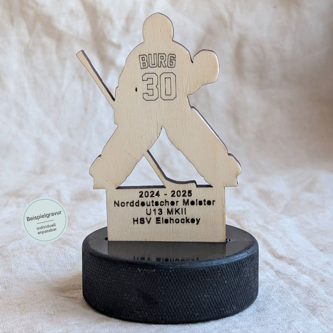 Detailaufnahme eines personalisierten Goalie-Pokals aus Holz auf Eishockey-Puck