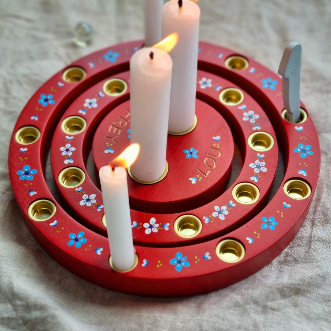 Geburtstagsring für Zwillinge mit 2 Lebenslichtern sowie den eingravierten Namen der Zwillinge in rot mit Blümchen - der Ring ist dargestellt mit brennenden Kerzen