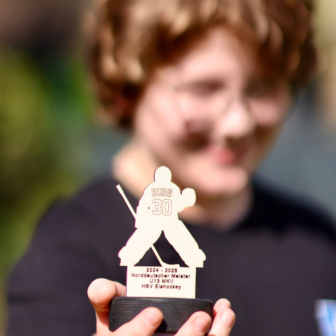 Kind hält Pokal mit Goalie-Motiv – handgemachter Eishockey-Pokal mit Gravur