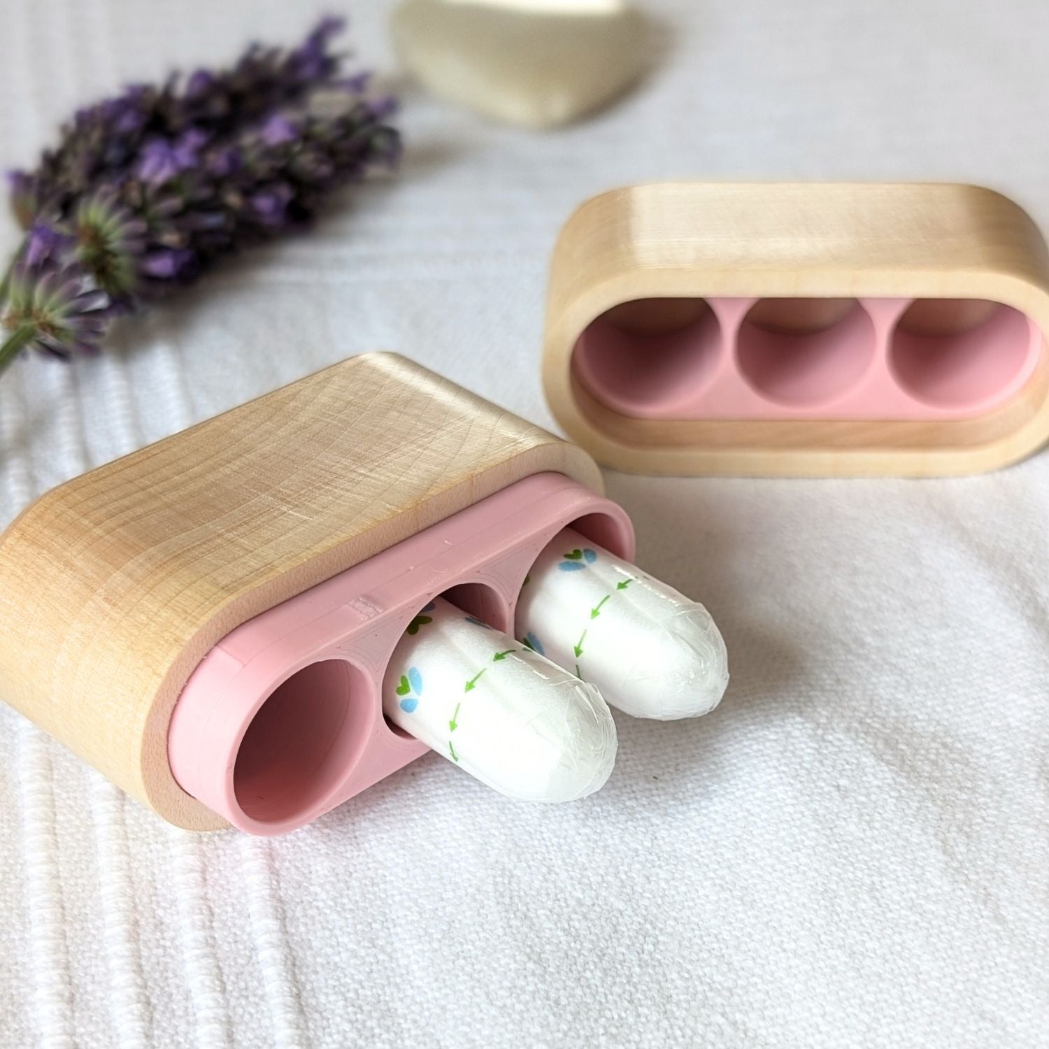 Geöffnete Tamponbox aus Ahornholz mit rosa Innenfach und zwei Tampons für den Alltagsgebrauc