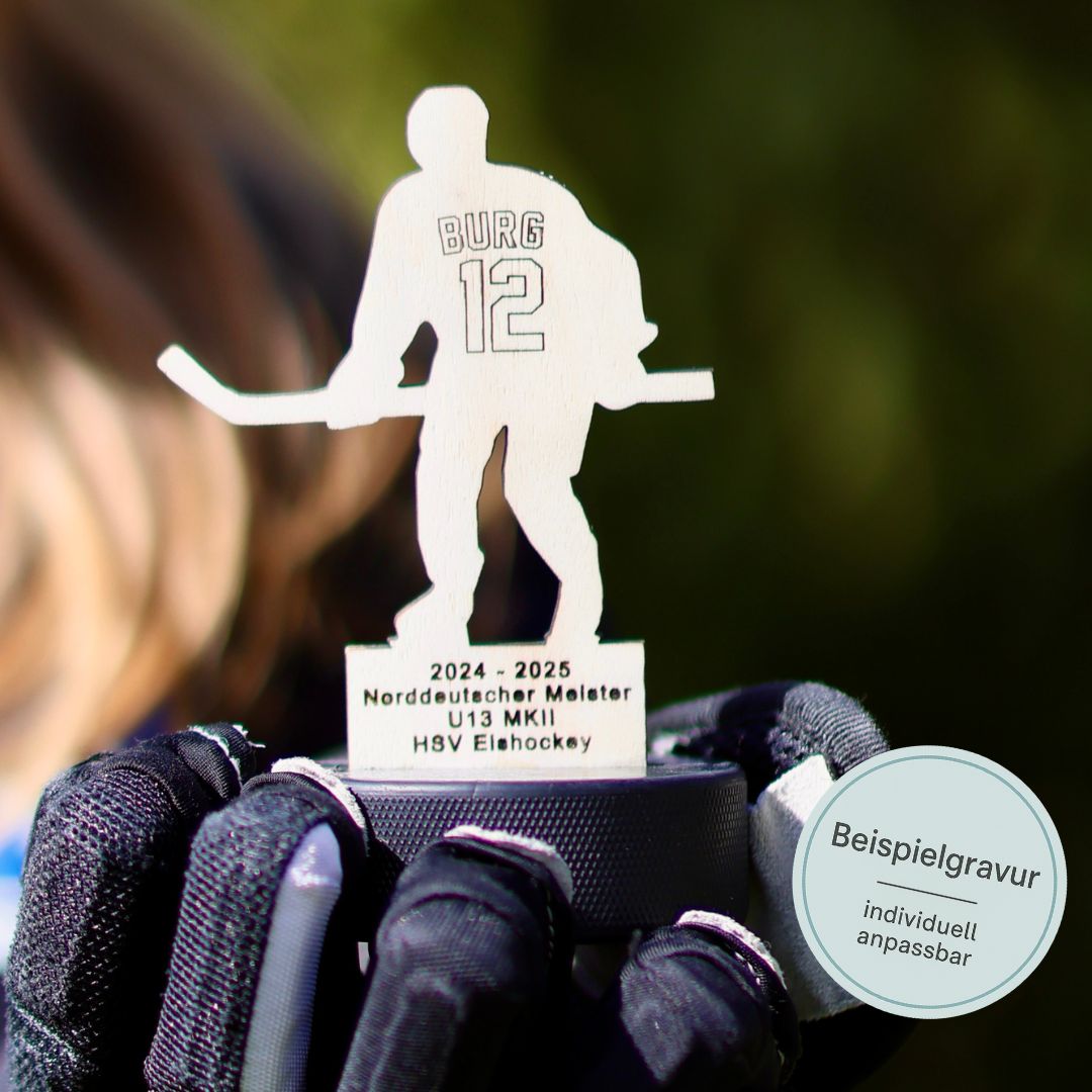 Ein Eishockey Pokal aus Holz wird auf einem Eishockey-Handschuh in die Kamera gehalten. Der Pokal ist personalisiert mit Name und Nummer des Spielers sowie des Turniers.