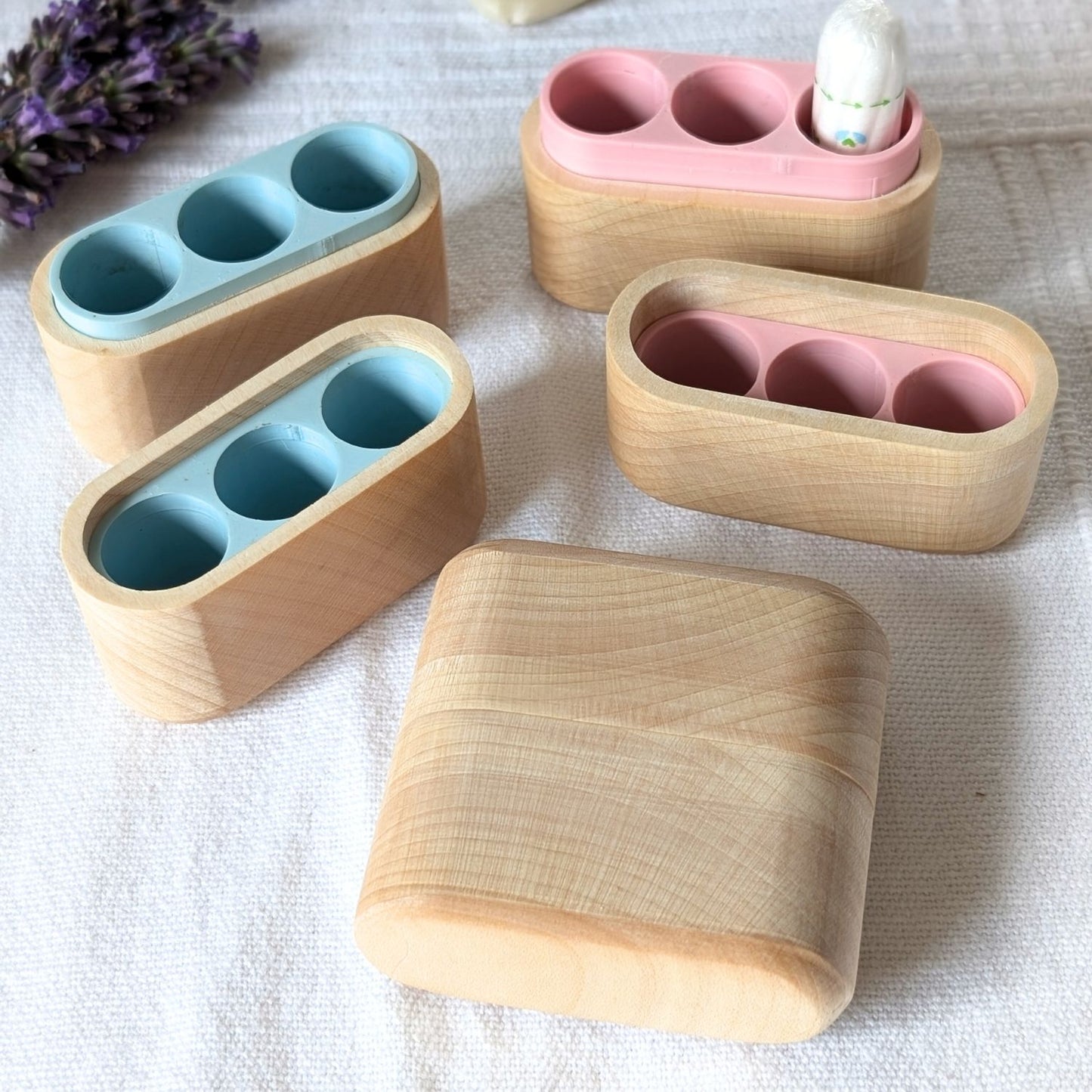 Tamponboxen aus Ahornholz mit rosa und hellblauem Innenfach, verschiedene Varianten im Überblick.