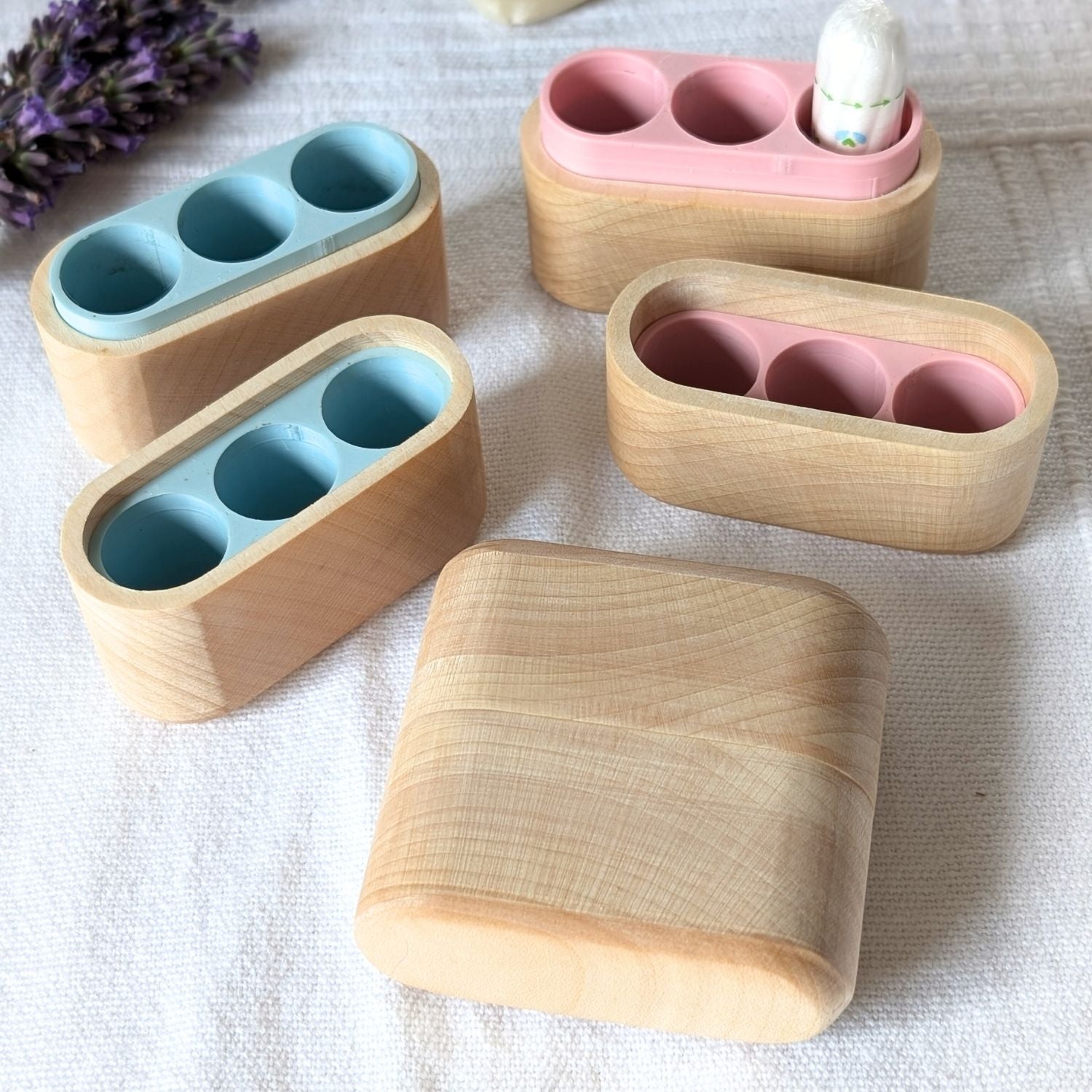 Tamponboxen aus Ahornholz mit rosa und hellblauem Innenfach, verschiedene Varianten im Überblick.