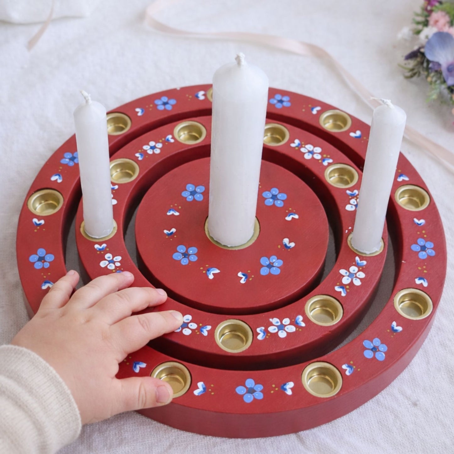 Kinderhand berührt handbemalten Geburtstagsring aus Holz mit Kerzen