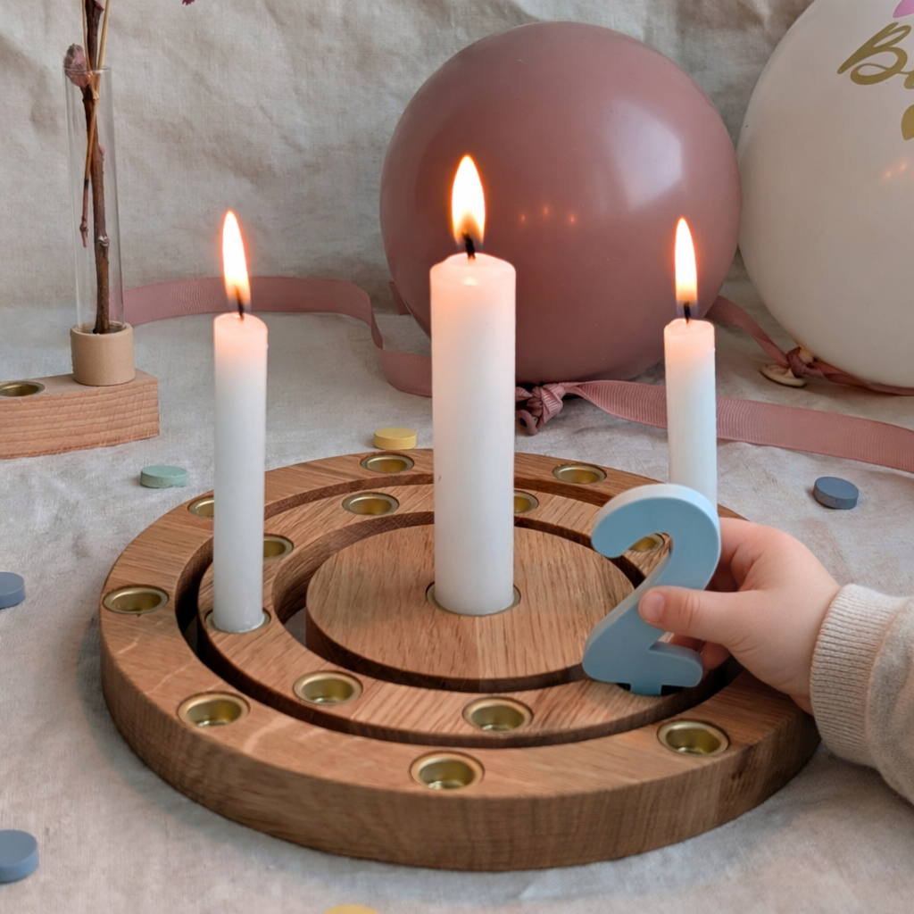 Kinderhand berührt Zahl 2 auf einem Geburtstagsring aus Eichenholz an