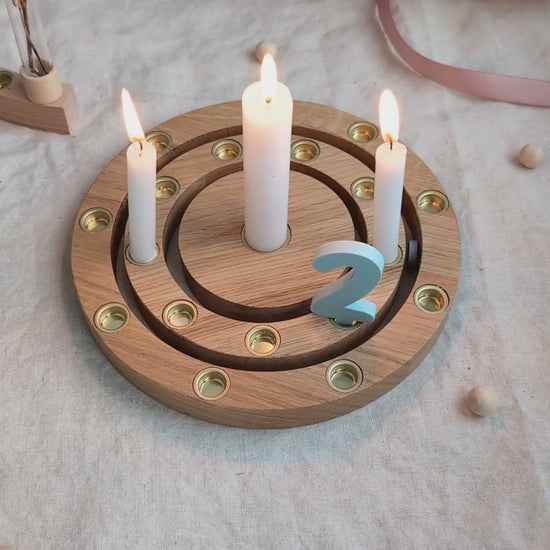 Geburtstagsring aus Eiche mit brennenden weißen Kerzen und graublauem Zahlenstecker